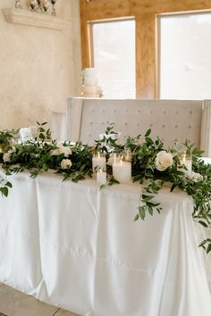 the table is set with candles and greenery for an elegant wedding reception in white