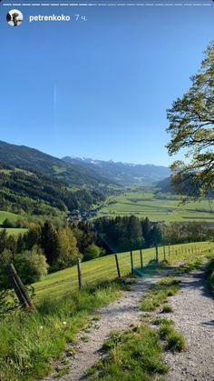 a dirt road going through a lush green valley