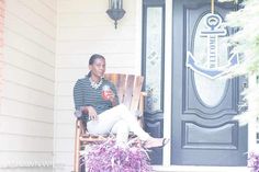 a woman sitting on a wooden chair in front of a door with purple decorations around her