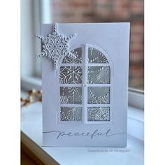 a white card with snowflakes on the window sill, and a star hanging from it's side