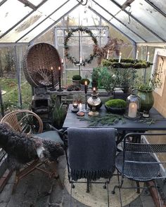 an outdoor dining area with plants and candles on the table, in a greenhouse style setting