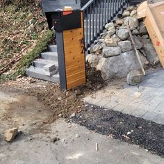 there is a pile of rubble next to the stairs and trash can on the sidewalk