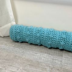 a blue crocheted pillow sitting on top of a wooden floor next to a window