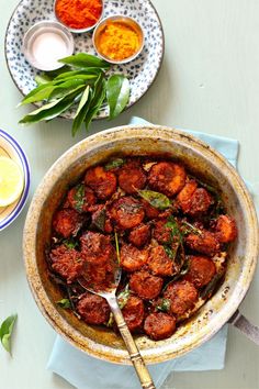 a bowl filled with meat sitting on top of a table next to bowls of sauce