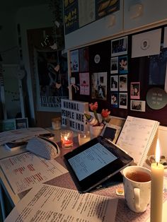 a tablet sitting on top of a table next to a lit candle and some papers