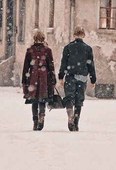 two people walking in the snow holding hands