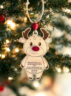 a christmas ornament hanging from a tree with lights in the background and a message written on it