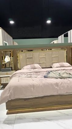 a large bed sitting on top of a white floor next to a wooden headboard