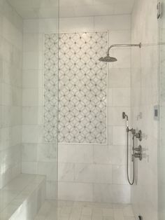 a walk in shower sitting next to a white tiled wall and floor with glass doors