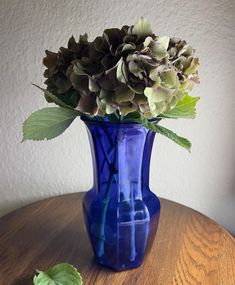 a blue vase filled with flowers on top of a wooden table