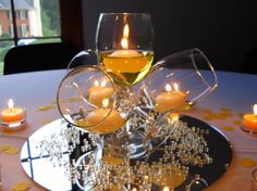 two wine glasses filled with candles on top of a table