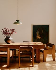 a dining room table with chairs and a vase on the table in front of it