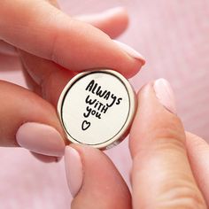 a person holding a button with the words always with you written on it in black ink