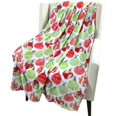 a white chair with a red and green apple print blanket on it's back