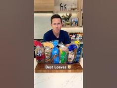 a man sitting at a counter in front of bags of food with the words best loaves on it