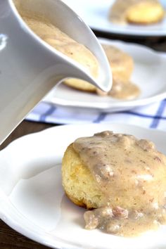 a person pouring gravy on top of a biscuit