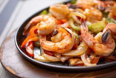 cooked shrimp and vegetable stir fry on a black plate, ready to be eaten or served