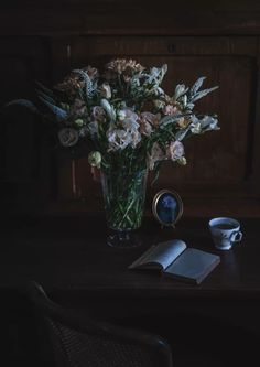 a vase filled with flowers sitting on top of a table next to an open book