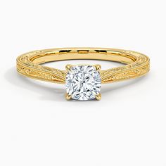 a yellow gold engagement ring with a diamond in the center and an intricate band around it