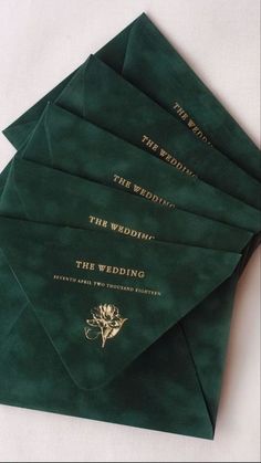 five green envelopes with gold lettering on them sitting next to each other, one for the bride and two for the groom