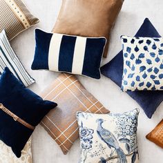 many different pillows are arranged together on the floor, including one with a blue bird