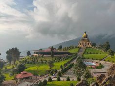 a scenic view of a green hill with a golden statue on it's top