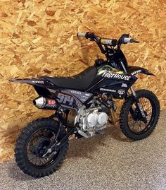 a dirt bike parked in front of a wooden wall