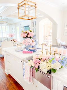 a white kitchen with pink and blue flowers on the counter