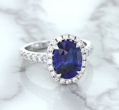 Lovely blue sapphire halo ring, reminiscent of the infamous Princess Diana sapphire engagement ring Simple, classic design makes it versatile for every day wear The perfect pop of color for when you decide to pop the question Perfect as an engagement ring or anniversary present Who wouldn't love a diamond halo ring with a blue sapphire center stone? Ever since Princess Di's famous engagement ring, women all over the world have discovered the beauty of blue sapphires. Our favorite aspect of this Oval Sapphire Ring Gia Certified, Gia Certified Oval Lab-created Sapphire Ring, Oval Sapphire Ring With Halo Setting In Platinum, Oval Lab-created Sapphire Jewelry With Halo Design, Oval Sapphire Halo Ring For Formal Occasions, Gia Certified Oval Sapphire Ring Gift, Classic Oval Sapphire Halo Ring, Blue Oval Gia Certified Halo Ring, Gia Certified Oval Lab-created Sapphire Diamond Ring