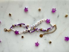 two bracelets with beads and charms on a white marble surface surrounded by gold stars