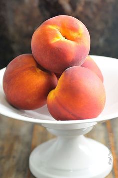 three peaches sitting on top of a white plate