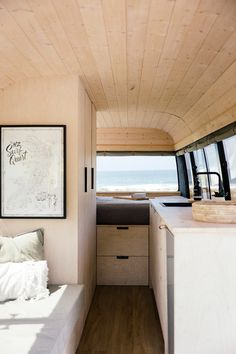 an interior view of a camper with wood paneling and white bedding on the side