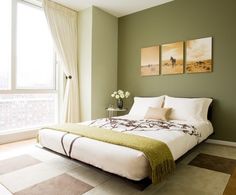 a green bedroom with white bedding and two paintings on the wall above the bed