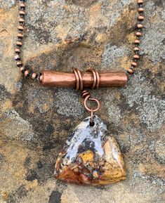 a necklace with a copper bead and a stone pendant hanging from it's side