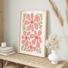 a framed flower print sitting on top of a shelf next to baskets and vases