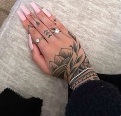 a woman's hand with tattoos on her left wrist and fingers, resting on the floor