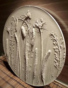 a white plate with flowers on it sitting on top of a wooden table next to a window