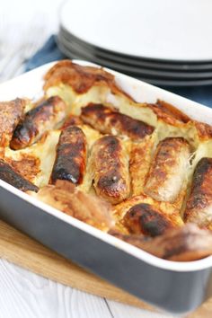 a casserole dish with meat and cheese in it sitting on a table next to plates