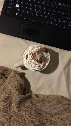 an open laptop computer sitting on top of a bed next to a cup of coffee