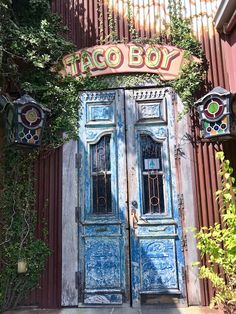 an old door with vines growing over it and the word taco boy on top