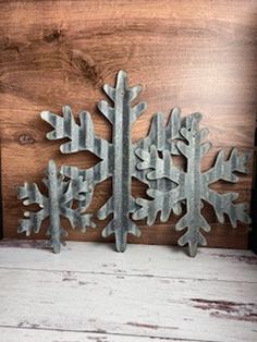 two metal snowflakes sitting on top of a wooden table