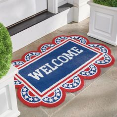 a welcome mat with the word welcome on it next to two potted planters