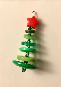 a green christmas tree ornament hanging from a hook on a white wall with a red star