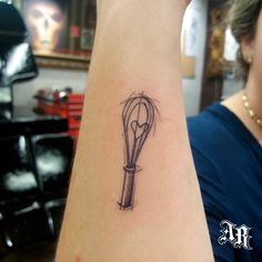 a woman's arm with a tattoo on it that has a whisk in it