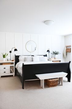 a white and black bedroom with a bed, nightstands, table and mirror on the wall