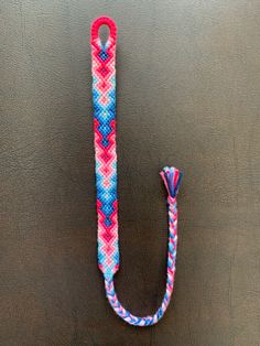 a pink, blue and white rope with a hook on it sitting on a surface