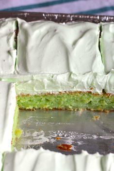 a cake with white frosting and green icing in a tin foil pan on top of a table