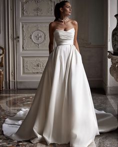 a woman in a white wedding dress standing on the floor