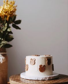 a white cake sitting on top of a wooden table next to a vase with yellow flowers