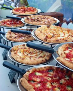 several pizzas are lined up on metal pans